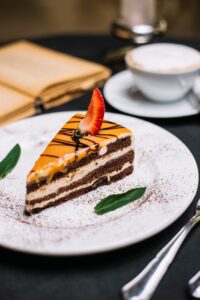 side-view-layered-chocolate-cake-covered-with-caramel-strawberry-slice-white-plate_141793-2986